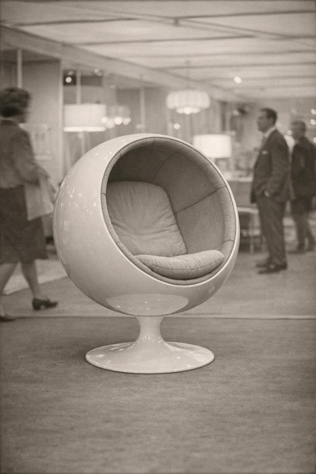A white fibreglass ball chair on a pedestal in an exhibition hall